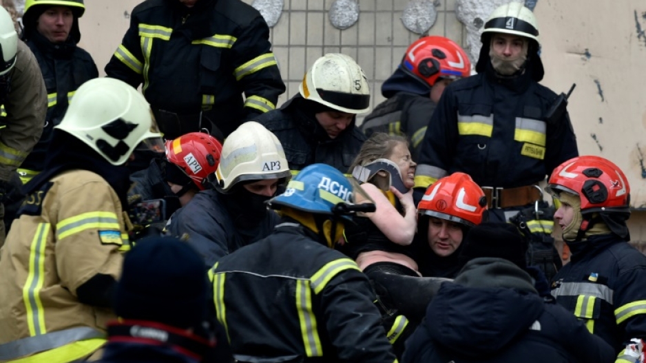 Rescuers carry a woman evacuated from the rubble of a residential building in Dnipro on Sunday