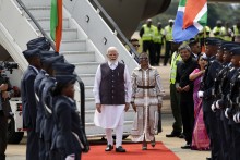 India's Prime Minister Narendra Modi (C-L) is welcomed by Minister in the South African Presidency Khumbudzo Ntshavheni (C-R) upon his arrival at the Air Force Base Waterkloof in Pretoria, on November 21, 2025 ahead of the G20 leader's Summit.