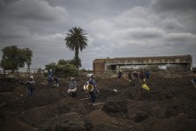 A man carries an empty bucket in a patch of land where artisanal miners look for gold outside Springs, Ekurhuleni, on February 15, 2026.