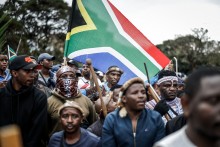 Members of the Zulu regiment known as the ‘Amabutho’ hold a South African flag as they march during a demonstration by the &amp;quot;March and March&amp;quot; movement. AFP/Marco Longari
