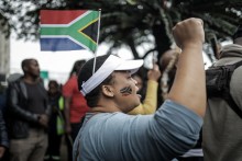 A protester gestures while wearing a South African flag over her head during a demonstration by the &amp;quot;March and March&amp;quot; movement. AFP/Rajesh Jantilal