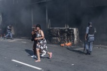 Members of the South African Police Service (SAPS) assist residents to take cover after clashes erupt between protesters and foreign nationals in Durban on October 8, 2026.