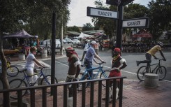 Traditional dancers stand idle as a couple of Dutch tourists and their guide push their bicycle past the Mandela House Museum in Vilakazi Street in Soweto, Johannesburg.