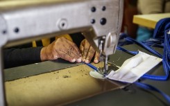 An elderly woman sews cotton fabric used to manufacture reusable face masks in Johannesburg's Alexandra township.