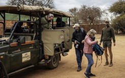 Tourists wearing face masks as a preventive measure against the spread of COVID-19 coronavirus get off from an open vehicle during a guided safari tour at the Dinokeng Game Reserve outside Pretoria, on 7 August 2020. 