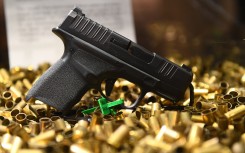 A Springfield Armory Hellcat 9mm micro-sized pistol that has fired 20,000 rounds is displayed with ammunition shell casings.