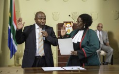 File: Des van Rooyen (L) raises his hand as he is sworn-in by Justice minister Sisi Khampepe as the new South African Finance Minister on December 10, 2015 at Union Builidngs in Pretoria, South Africa. 