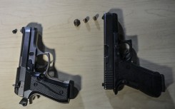 File: View of non lethal gun (L) and a 9mm pistol in a shooting range in Bogota, on September 17, 2021. Juan BARRETO / AFP