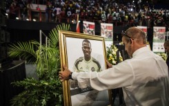 A memorial marshall places the portrait of Senzo Meyiwa during a memorial for the late National Team Captain and Orlando Pirates goalkeeper Senzo Meyiwa, Olympic champion Mbulaeni Mulaudzi and boxer Phindile Mwelase at the Standard Bank Arena in Johannesburg Central District on October 30, 2014