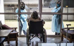 Relatives chat through a window to a wheelchair-bound woman at an old age home in Johannesburg. Under Level 2 lockdown regulations, restrictions on family and social visits have been lifted.