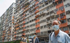 Pedestrians cross a road past apartment blocks in Hong Kong's To Kwa Wan area during intense heat