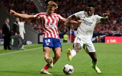 Real Madrid's Brazilian forward Vinicius Junior vies with Atletico Madrid's Spanish midfielder Marcos Llorente (L) during the derby between Atletico de Madrid and Real Madrid CF at the Wanda Metropolitano stadium in Madrid on September 18, 2022.