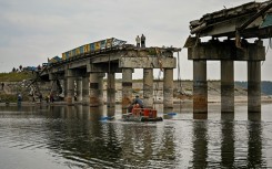 Local residents cross the Donets river next to a destroyed bridge 