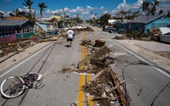 A man walks pass debris scattered on Pine Island Road in the aftermath of Hurricane Ian in Matlacha, Florida 