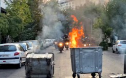 Street bins burn during clashes in Tehran