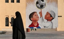 A woman walks past a mural in the Katara Cultural Village, in Qatar's capital Doha, on October 11, 2022 ahead of the FIFA 2022 football World Cup