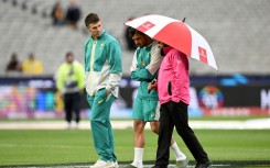 Australia's Mitchell Marsh (L) and Marcus Stoinis chat with umpire Aleem Dar at a wet MCG