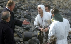 Spain's former king Juan Carlos talks to volunteers helping clean up the 'Prestige' oil spill at Muxia in 2002