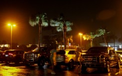 People fight the wind in a parking lot before Hurricane Nicole makes landfall in Jensen Beach, Florida 