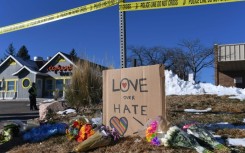 Bouquets of flowers and a sign reading "Love Over Hate" are left near Club Q following the mass shooting