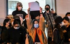 A man is arrested as people gather on a street in Shanghai where protests against China's zero-Covid policy took place the night before