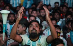 Football fans react as they watch the World Cup match between Poland and Argentina on a big screen in Dhaka