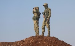 Turkish-backed Syrian fighters keep watch on the front line with Kurdish forces in Tal Rifaat, awaiting orders from Turkish President Recep Tayyip Erdogan on whether to proceed with a threatened ground offensive