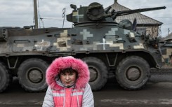 Lisa Shtanko, 8, looks on as a military vehicle passes in front of her house in the Ukrainian city of Lyman