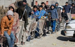 Afghan boys and men line up with wheelbarrows to receive food aid in Kabul, where the Taliban have banned women from working with NGOs