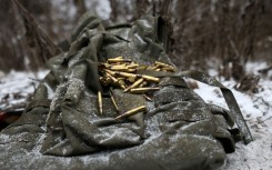 A medic kneels in the snow over one of the wounded's armoured vest, gathering cartridges and searching his identification documents