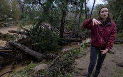 Amberlee Galvin stands next to evidence of the flooding that has ravaged the town of Felton 