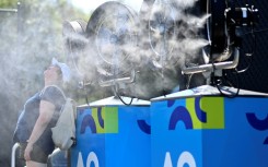 A woman cools off in front of mist cooling fans at the Australian Open