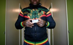 An undocumented worker from Mali holding his access card to the Olympic construction site where he worked 