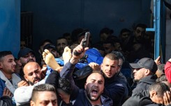 A man fires his gun into the air as Palestinians carry the body of one of the victims killed during an Israeli raid on the West Bank's Jenin refugee camp