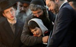 Aharon Natan, the father of 14-year-old Asher Natan, a victim of a shooting attack in east Jerusalem on January 27, 2023, mourns with her other son during his funeral at a cemetery in Jerusalem, on January 29, 2023