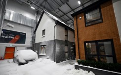 Simulated snow covers a car and the walls of one of two houses built in a lab to develop future heating solutions that will use less energy and help meet climate goals
