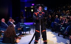 The spacesuit modeled by Jim Stein featured a cover layer in all black with blue and orange trim which Axiom Space said was required to 'conceal the suit's proprietary design'