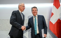 Credit Suisse chairman Axel Lehmann (L) shakes hands with UBS chairman Colm Kelleher after a press conference announcing the takeover