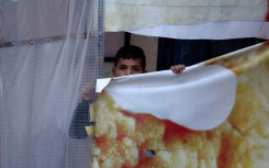A Palestinian boy peeps at Israeli soldiers patrolling Huwara
