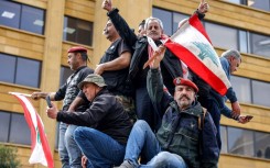 Protesters wave Lebanon's flag during a demonstration by retired army and security forces veterans on Wednesday, demanding inflation-adjustments to their pensions