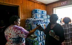 A volunteer carries jugs of water and supplies from a makeshift clinic and relief center in Rolling Fork, Mississippi