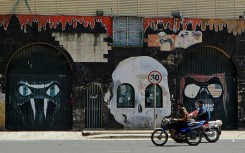 Motorcyclists drive past the closed Saudi embassy in Sanaa