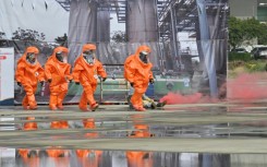Rescuers in protective equipments walk past a mock collapsed nuclear power plant during a civilian drill while imitating a Chinese attack in Taichung in April 2023