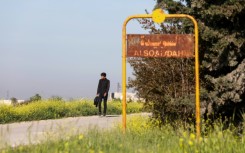 A man walks past the sign of Al-Suwaydah village near Jarablus in Syria's Aleppo province after the US helicopter raid