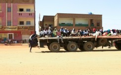 People fleeing street battles in Khartoum are transported on the back of a truck