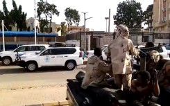A convoy evacuating foreign citizens leaves Khartoum towards Port Sudan watched by soldiers