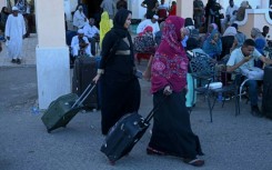 People wait with their luggage at Port Sudan ahead of their evacuation by sea
