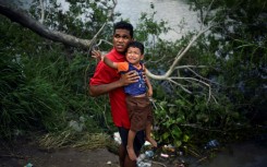 A migrant carrying a child tries to get to the US through the Rio Grande River as seen from Matamoros, state of Tamaulipas, Mexico, on May 11, 2023