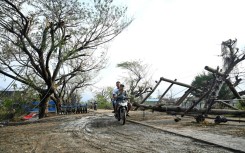 Two men drive past fallen utility poles in Kyauktaw in Myanmar's Rakhine state, hit by Cyclone Mocha