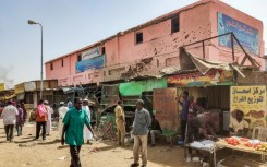 People walk past a medical centre riddled with bullet holes in the Sudanese capital's Souk Sitta